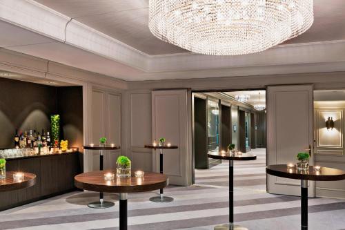 a hotel lobby with tables and a chandelier at Renaissance Vienna Schönbrunn Hotel in Vienna