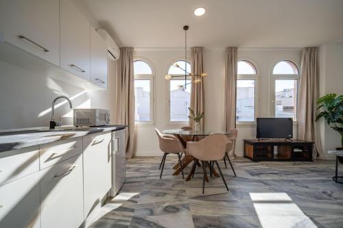 eine Küche mit weißen Schränken und einem Tisch mit Stühlen in der Unterkunft William Martin Apartments in Huelva
