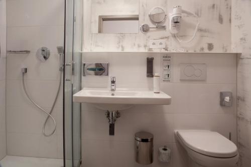 a bathroom with a sink and a toilet and a shower at Hotel Koruna in Chlumec nad Cidlinou