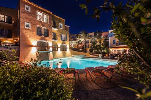 a swimming pool with chairs and buildings at night at Hotel Byblos Saint-Tropez in Saint-Tropez