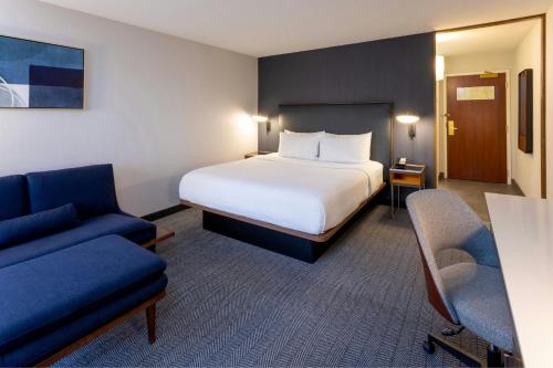 a hotel room with a bed and a couch at Courtyard Minneapolis St. Paul/Roseville in Roseville