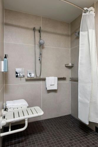 a bathroom with a shower with a bench and a shower curtain at Courtyard by Marriott Phoenix Airport in Phoenix