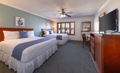 a bedroom with two beds and a flat screen tv at Brisas Del Mar Inn at the Beach in Santa Barbara