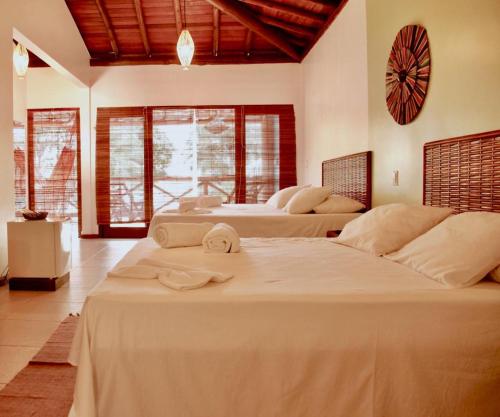 a bedroom with two beds with white sheets at Pousada Iyalodê in Marau