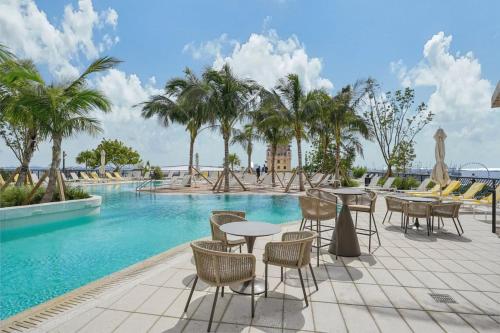 a pool with tables and chairs and palm trees at NEW Luxury Bay View Downtown Studio in Miami