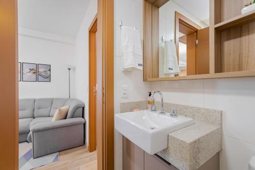 a bathroom with a white sink and a couch at Condomínio Niagara On The Lake | Gonzaga Stays in Curitiba