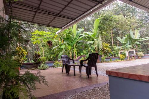 three chairs sitting around a table in a garden at Traditional house - Agri farm stay in Thodupuzha