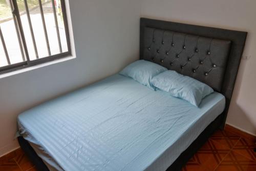 a bed with a headboard and blue sheets and a window at Apto Acogedor Cerca Metrocable in Medellín
