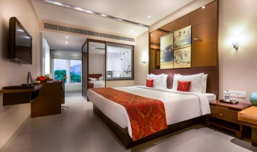 a hotel room with a large bed and a television at Regency Sameera Vellore by GRT Hotels in Vellore