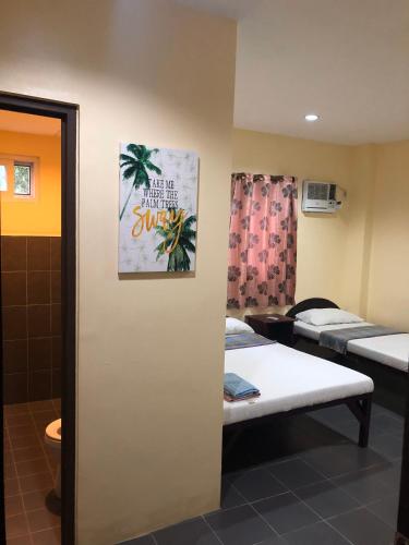 a room with three beds and a poster on the wall at CNC DIVE RESORT at CEBU in Lapu Lapu City
