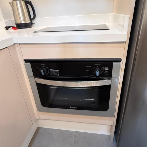a kitchen with a black oven in a cabinet at Loft em Xangri-Lá com piscina aquecida in Xangri-lá
