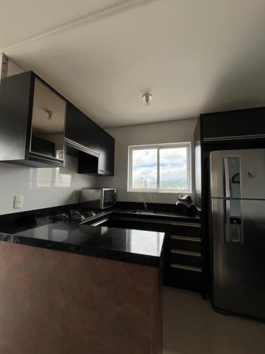 a kitchen with black counter tops and a window at Residencial Lunit in Camboriú