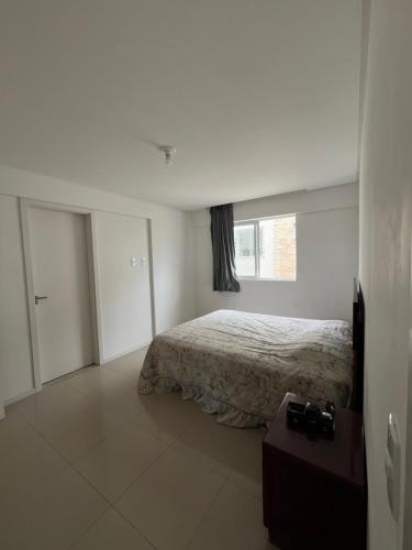 a white bedroom with a bed and a window at Residencial Lunit in Camboriú