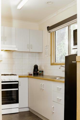 a kitchen with white cabinets and a black refrigerator at BIG4 Albury Tourist Park in Albury