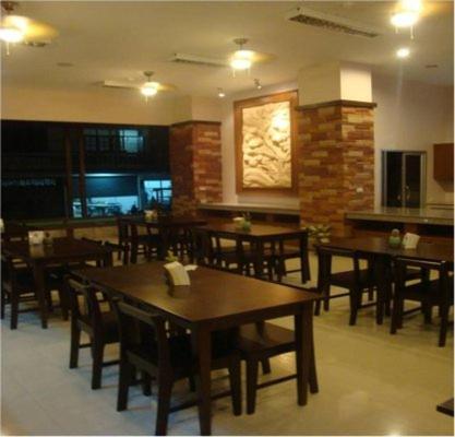 a restaurant with wooden tables and chairs in a room at U Inn in Khon Kaen