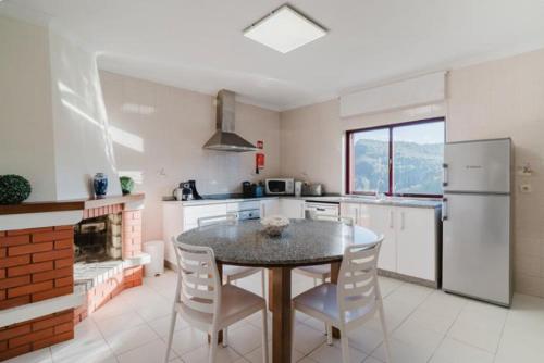 a kitchen with a table and chairs and a refrigerator at Alojamento Casa da Pedra Verde in Vieira do Minho