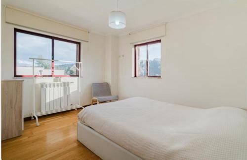 a white bedroom with a bed and a chair at Alojamento Casa da Pedra Verde in Vieira do Minho
