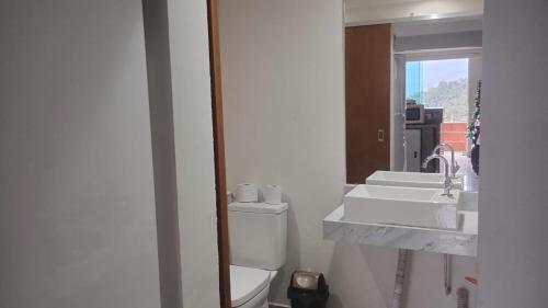 Un baño con lavabo, inodoro y espejo. en Casa temporada, en Ilhabela
