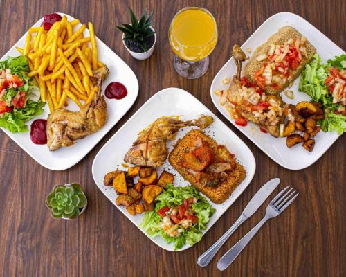 een tafel met drie borden eten en frietjes bij Villa serenité lac rose avec cuisinier ,piscine et jacuzzi terrasse vue lac in Ouayembame