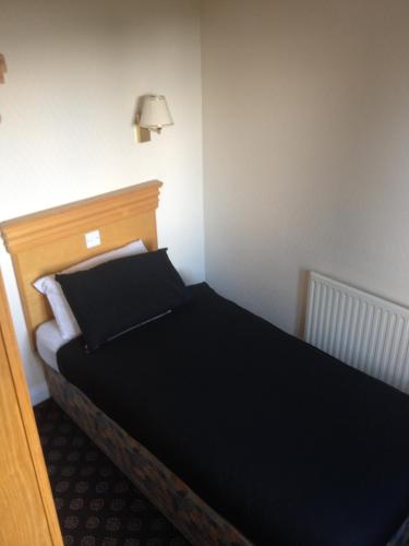 a bedroom with a bed with black sheets and a lamp at The Miners Arms in Leeds
