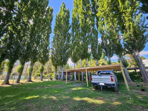 a white truck parked under a bunch of trees at Acogedora Casa Frente al Lago Rapel in Las Cabras