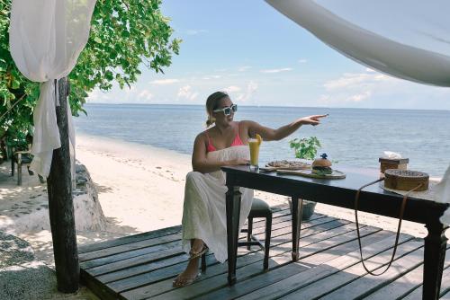 a woman sitting at a table on the beach at Patrick's on the Beach Resort in General Luna