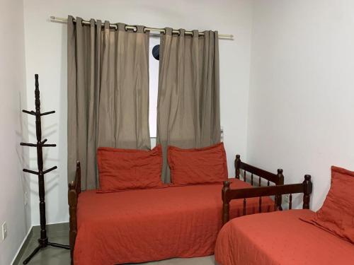 a bedroom with two beds with red sheets and a window at Casa Rebello - Pousada in Itajaí