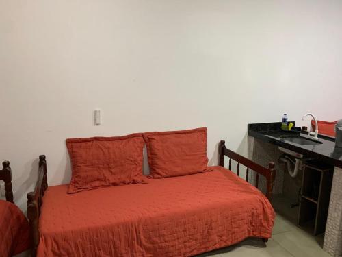 a bedroom with a bed with orange sheets and a desk at Casa Rebello - Pousada in Itajaí