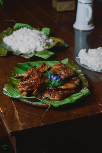 a plate of chicken and rice on a wooden table at Patrick's on the Beach Resort in General Luna