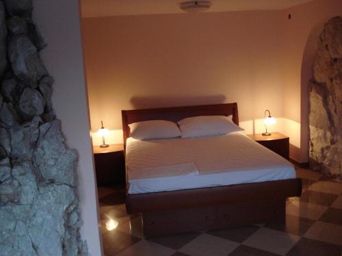 a bedroom with a bed with two lamps on both sides at Old Town Vrbnik Villas in Vrbnik