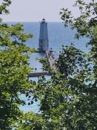 a lighthouse in the middle of the water with trees at Great Lakes Getaway - Incredible Lakefront! in Frankfort
