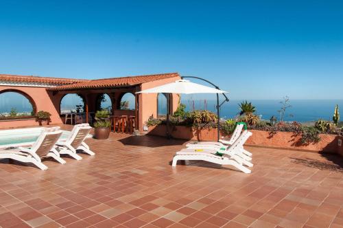 a group of white chairs and an umbrella on a patio at Mansion Bandama by VillaGranCanaria in Tafira