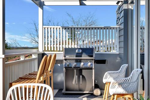 a patio with a grill and chairs on a balcony at Seven Mile View Gerroa in Gerroa