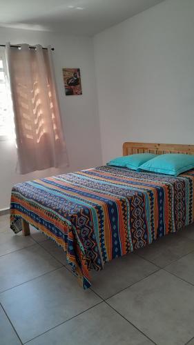 a bed with a colorful blanket on it in a room at Hébergement T3 COSY WOUSIRE in Les Abymes