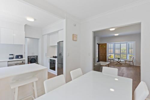 a kitchen and dining room with a white table and chairs at Elegant 3-Bed Home Steps from Sunny Glenelg Beach in Glenelg