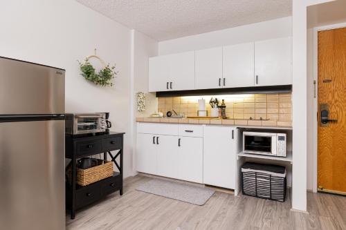 a kitchen with white cabinets and a refrigerator at Bishop Suites at Executive Centre in Honolulu