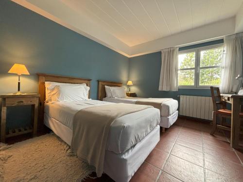 1 Schlafzimmer mit 2 Betten, einem Tisch und einem Schreibtisch in der Unterkunft Rio Tarde Casa Patagonica in Lago Posadas