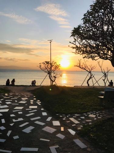 a sunset over the water with people sitting on a bench at Charung by The Sea in Haad Rin