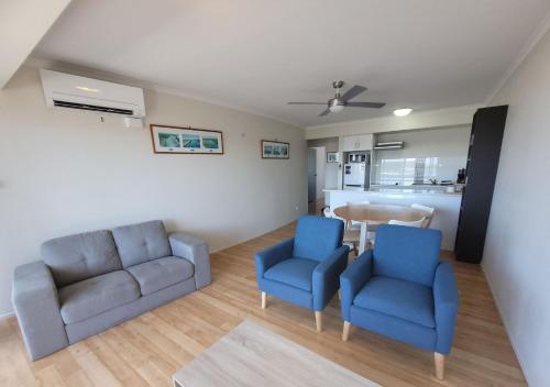 a living room with two blue chairs and a table at Holiday In Husky - 2 Bedroom Apartment located in the centre of town in Huskisson