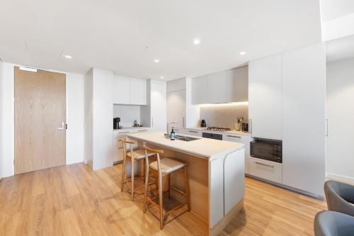 a kitchen with white cabinets and a counter with stools at Oceanview 2BR 2BA in The Miles Residences Kirra in Gold Coast
