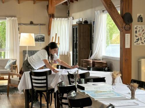 Eine Frau, die einen Tisch im Esszimmer legt. in der Unterkunft Rio Tarde Casa Patagonica in Lago Posadas