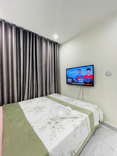 a bedroom with a bed with a tv on the wall at Căn hộ Studio GH2 Vinhomes Grand Park in Long Bình