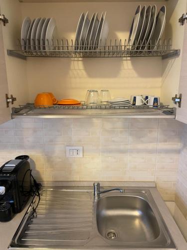 a kitchen with a sink and a shelf with utensils at Appartamento nuovo e moderno in Cesano Maderno
