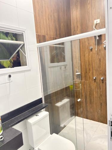 a bathroom with a toilet and a glass shower at Pousada Vale do Sol in Pariqueraçu
