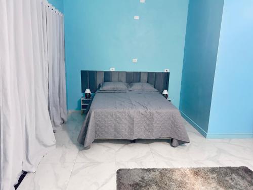 a bedroom with a large bed with a blue wall at Pousada Vale do Sol in Pariqueraçu