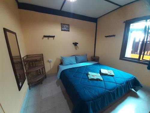 a bedroom with a blue bed and a window at Sabai ça Baille Guesthouse in Pakse