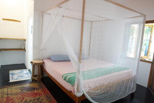 a bedroom with a bed with a mosquito net at Surf &Turf Arugam Bay in Arugam Bay