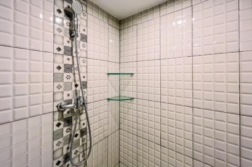 メダンにあるGood Deal and Homey Studio De Prima Apartment By Travelioの白いタイル張りのバスルーム(シャワー付)