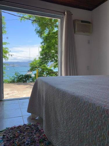 a bedroom with a large window with a view of the ocean at Suites com vista para o Mar in Angra dos Reis