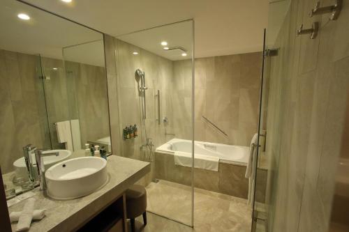 a bathroom with a shower and a sink and a tub at Hotel Royal-Nikko Taipei in Taipei
